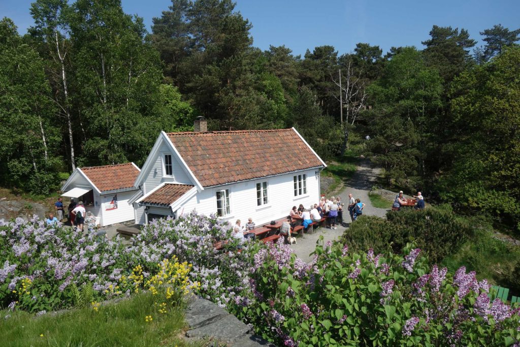 Hvitt hus med folk som sitter utenfor på røde benker